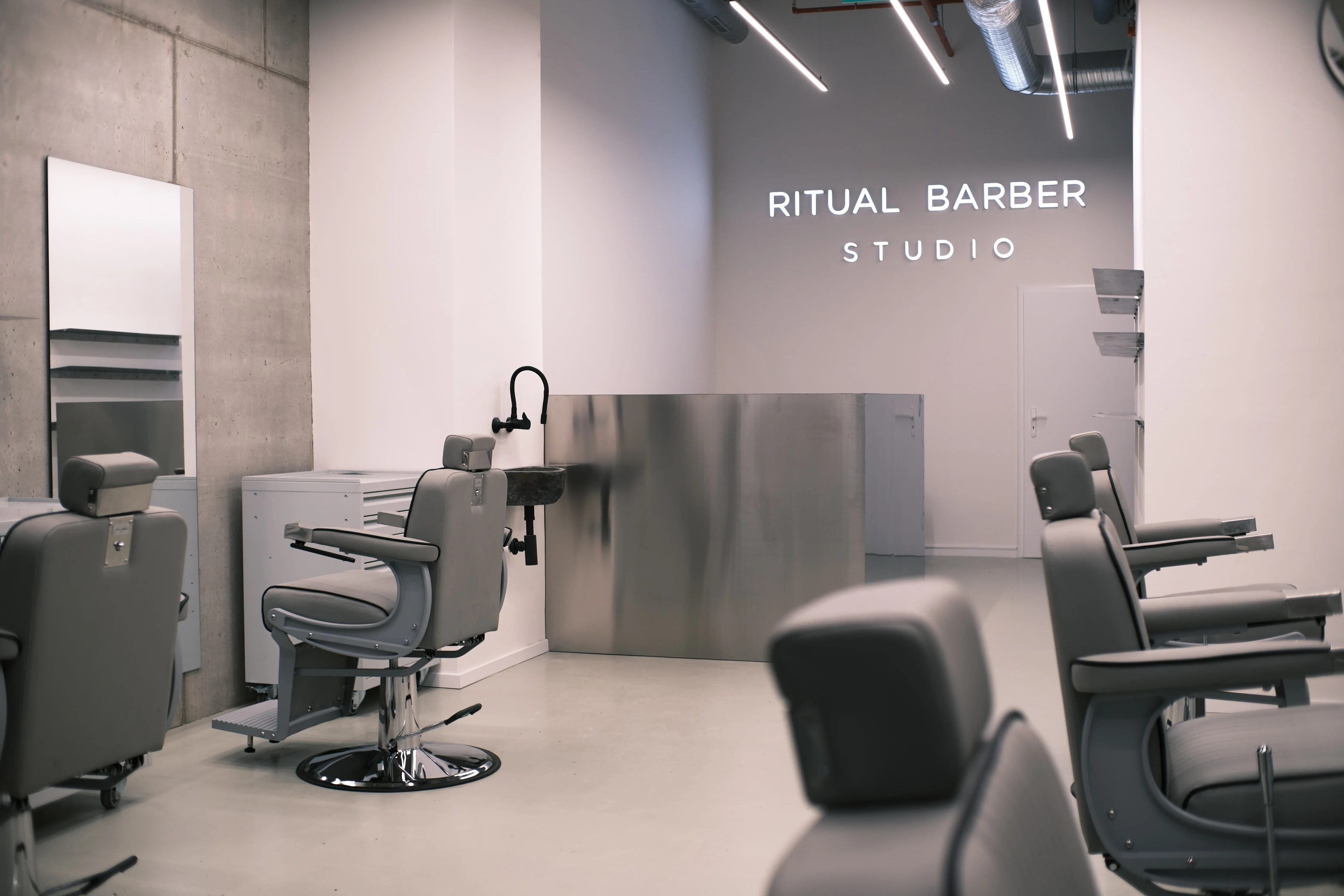 Recepce Ritual Barber Studia s podsvíceným nápisem a barberskými křesly
